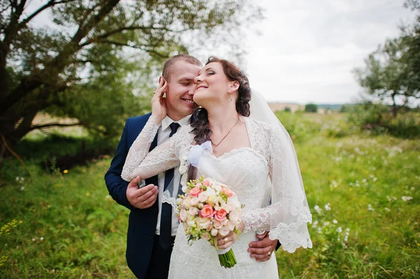 Pareja de boda en hierba alta y cerca del árbol — Foto de Stock