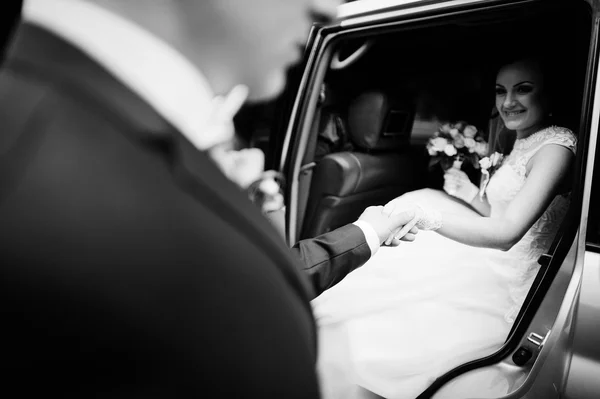 Le marié prend la main de la mariée dans la voiture — Photo