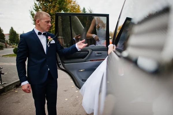 O noivo leva a mão da noiva no carro — Fotografia de Stock