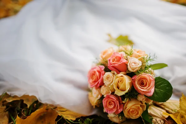 Ramo de boda fondo vestido de novia en hojas de otoño amarillo —  Fotos de Stock