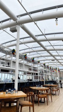 Chicago, Illinois, ABD - 25 Aralık 2024 Şık Şikago restoranı Offshore Çatı Barı ve ahşap masaları, şenlikli dekorları ve havadar cam tavanı olan yemek alanı.