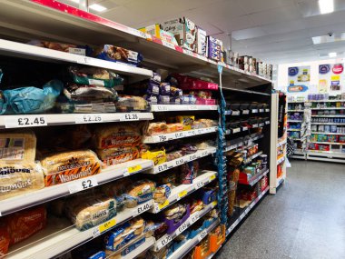Manchester, İngiltere - 26 Eylül 2025: Ekmek ve pişirilmiş ürünler ve fiyat etiketleri ve ambalajlı iyi stoklanmış Tesco market koridoru.