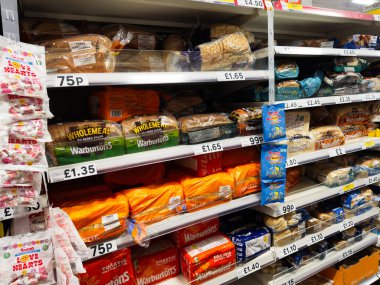 Manchester, İngiltere - 26 Eylül 2025: Dolu bir market ortamında etiketli ve paketlenmiş çeşitli ekmekler.