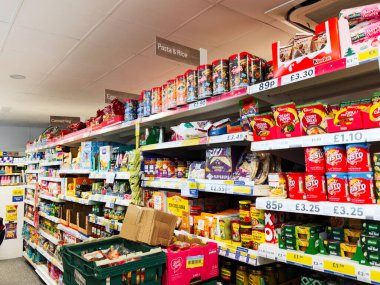 Manchester, İngiltere - 26 Eylül 2025: Bright Tesco süpermarket koridoru konserve yiyecekler, kutulanmış yemekler ve fiyat etiketleriyle dolu 