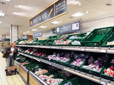 Manchester, İngiltere - 26 Eylül 2025: Günlük alışveriş yapan kişi iyi stoklanmış bir Aldi süpermarket koridorunda taze meyve ve sebzelere göz atıyor. 