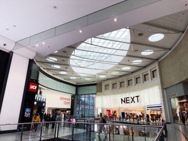 Manchester, İngiltere - 26 Eylül 2025: Geniş bir NEXT mağaza önü ve takas alanına sahip, modern mimari ve işlek müşteriler sergilenen parlak Arndale alışveriş merkezi.