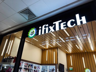 Manchester, İngiltere - 26 Eylül 2025: Camdan vitrin önü, logo, ahşap paneller ve parlak ışıklandırma ile modern iFixTech teknik tamir atölyesi.