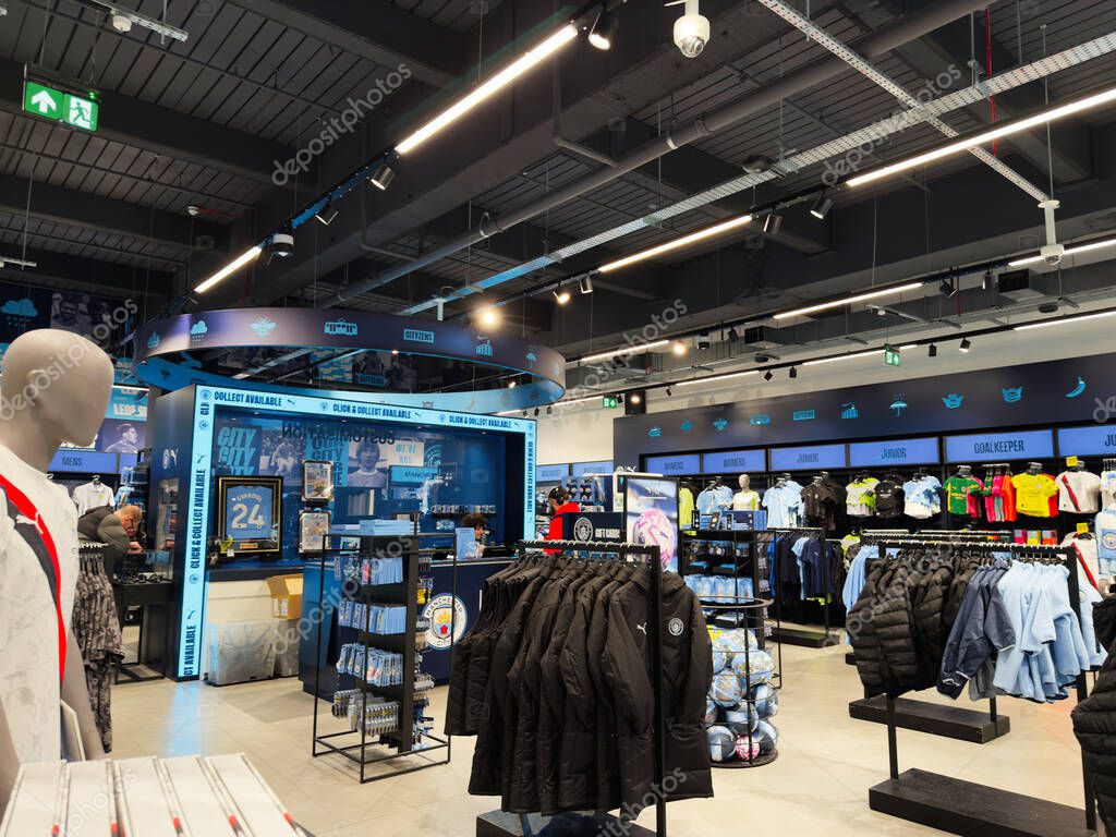 Manchester, UK - September 26, 2025: Bright retail Man City space showcasing athletic apparel and gear with blue accents and organized merchandise throughout.