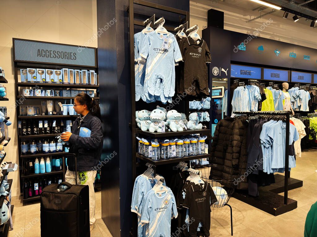 Manchester, UK - September 26, 2025: Bright store scene with blue Manchester City jerseys, plush bears, and water bottles for fans and shoppers.