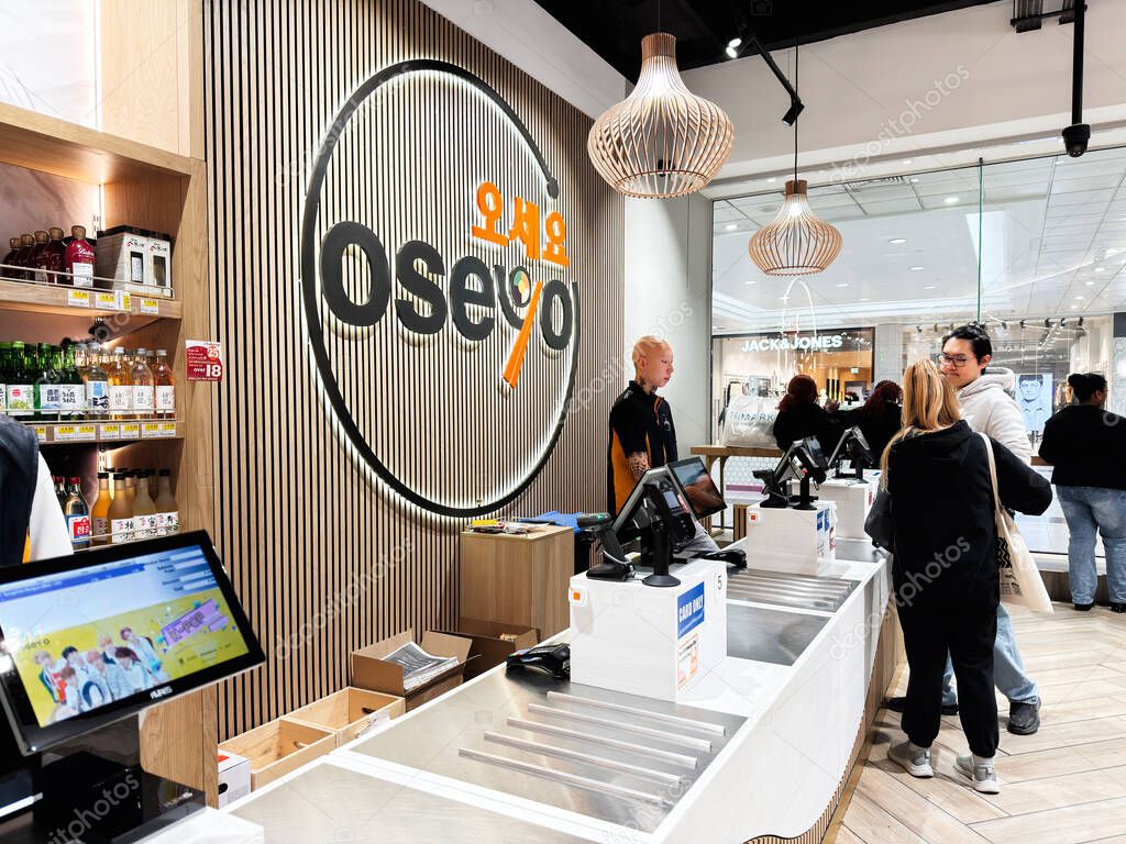 Manchester, UK - September 26, 2025: Bright Oseyo shop scene with a large circular logo, wooden slat wall, hanging lamps, and customers at the checkout counters.