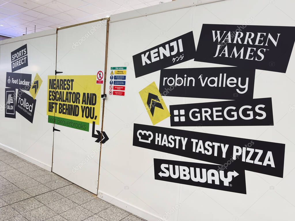 Manchester, UK - September 26, 2025: A busy wall covered with bold logos and signs creating an urban visual.
