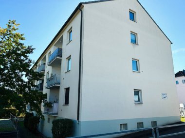 Banneux, Belçika - 20 Ekim 2023: Balkonları, ağaçları ve açık mavi gökyüzü altında parlak beyaz bir cephesi olan Belçika 'daki konut binası.