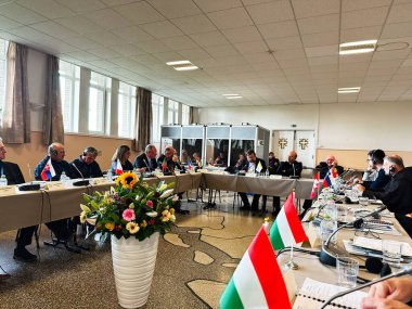 Banneux, Belçika - 20 Ekim 2023: Delegeler resmi bir toplantı için Belçika 'da uzun bir konferans masasının etrafında toplandılar, bayraklar sergileniyor.