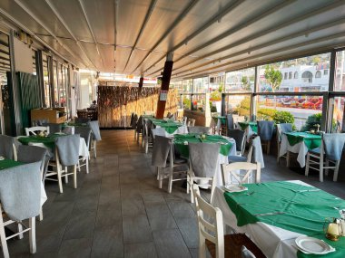 Paralimni, Kıbrıs - 18 Temmuz 2024: Paralimni 'de günlük yemek için yeşil çarşaflar ve beyaz sandalyeli güneşli yemek alanı.