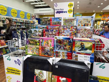 Manchester, İngiltere - 26 Eylül 2025: Neşeli bir dükkanda renkli yapboz gösterisi, çeşitli bulmaca setlerini keşfeden müşteriler ve hediye eşyalar.