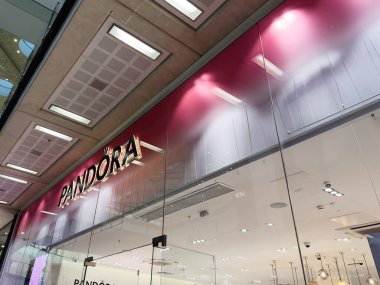 Manchester, İngiltere - 26 Eylül 2025: Cam mağaza önü, parlak ışıklandırma ve zarif mücevher vitrinleri ile lüks Pandora mağaza iç mimarisi.