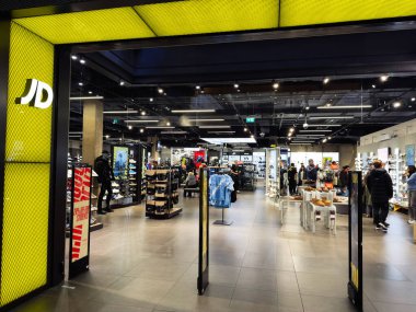 Manchester, İngiltere - 26 Eylül 2025: Parlak ışıklandırma, vitrinler ve ayakkabı ve moda gezen müşteriler ile yoğun perakende mağazası.