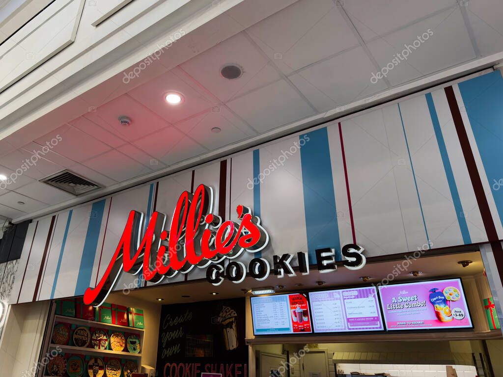 Manchester, UK - September 26, 2025: Colorful Millie's Cookies cookie shop exterior with bold red logo, striped facade, and menu boards.