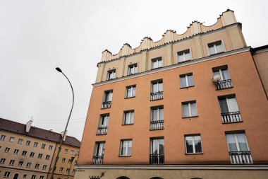 Tarnow, Polonya - 10 Ekim 2025 Tarnow Polonya 'da turuncu konut binası balkonları ve uzun kıvrımlı sokak lambası