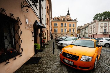 Tarnow, Polonya - 10 Ekim 2025 Tarnow Polonya 'da tarihi renkli binaların yanına park edilmiş Orange Audi TT arabası.