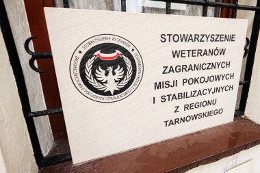 Tarnow, Polonya - 10 Ekim 2025: Dairesel amblem ve bir pencerenin yanına asılmış büyük Polonya yazıtlı taş bir plaket. Stowarzyszenie Weteranw Misji Zagranicznych. 