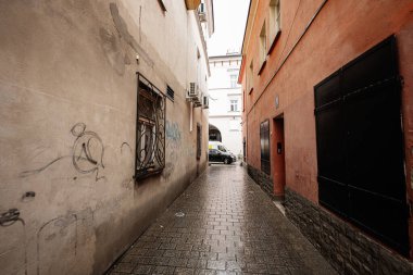 Tarnow, Polonya - 10 Ekim 2025 Tarnow Polonya 'da sakin bir sokak, ıslak sokaklar ışığı, duvar yazılarını, parmaklıklı pencereleri yansıtıyor.