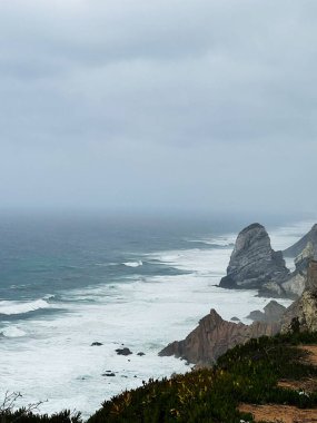 Portekiz 'deki dramatik Roca Burnu sahnesi engebeli uçurumları, kayalık kıyıları ve sisli Atlantik dalgalarını gösteriyor..