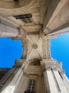 Lizbon, Portekiz - 28 Eylül 2025: Lizbon, Portekiz 'deki etkileyici taş Rua Augusta kemer yolu ve sütunları mavi gökyüzüne karşı yer seviyesinden ele geçirildi.