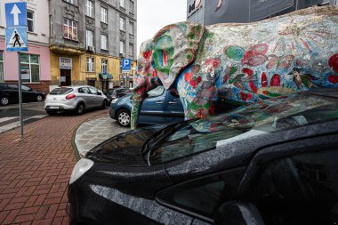 Tarnow, Polonya - 10 Ekim 2025 Yoğun bir Tarnow caddesinde park halindeki arabaların yanında çiçeklerle kaplı canlı fil heykeli.