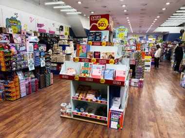 Manchester, İngiltere - 26 Eylül 2025: Müşteriler yoğun bir perakende mağazasının içindeki parlak raflardaki oyuncaklara ve kitaplara göz atıyorlar.