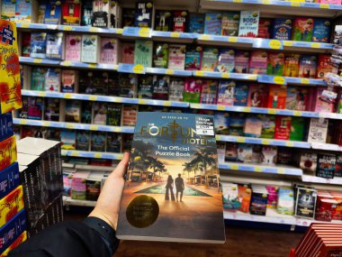Manchester, İngiltere - 26 Eylül 2025: Fortune Hotel Resmi Bulmaca Defteri, bir alışverişçinin kapak olması nedeniyle işlek bir kitapçıda parlıyor.