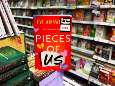 Manchester, İngiltere - 26 Eylül 2025: Eve Ainsworth 'un eserleri yoğun bir kitapçıda sergileniyor, koyu kırmızı kapak duygu ve merakı çağrıştırıyor.