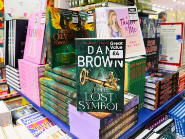 Manchester, İngiltere - 26 Eylül 2025: Yazar Dan Brown, The Lost Symbol, hareketli bir kitapçıda renkli kitapların arasında oturuyor.