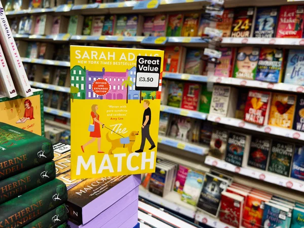 Manchester, İngiltere - 26 Eylül 2025: Sarah Adams The Match, diğer romanların arasında işlek bir kitapçıda sergilenen parlak sarı bir kitabın kapağında.
