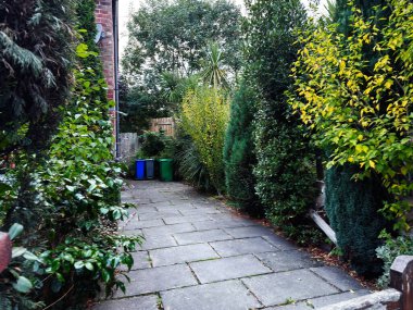 Manchester 'da sık bitkiler, kaldırım taşları ve varillerle dolu sessiz bir bahçe yolu..