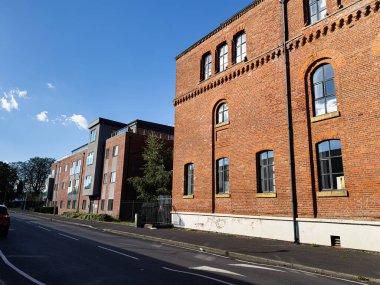 Kırmızı tuğlalı binalar güneşli bir günde sakin bir Manchester caddesini çevreleyen modern apartmanlarla kaplıyor..