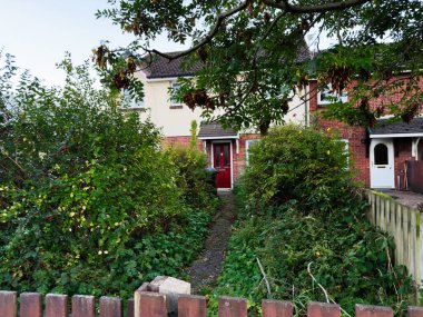 Manchester banliyösündeki çitler ve tuğla evler arasındaki yemyeşil bahçe yolu.