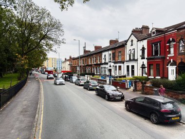 Manchester, İngiltere - 29 Eylül 2025: Park etmiş arabaları, kırmızı tuğlalı terasları ve kaldırımda uzanan ağaçlarıyla Manchester Moss Ln caddesi. Verdene Oteli