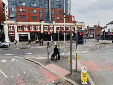 Manchester, İngiltere - 29 Eylül 2025: İnsanların kesişme noktasından, trafik ışıklarından ve Rusholme Place 'in tuğla ve cam vitrinlerinin karışımından geçtiği Manchester sahnesi