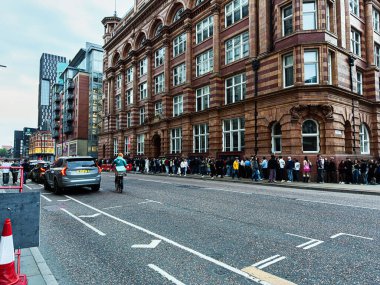 Manchester, İngiltere - 29 Eylül 2025: Manchester 'da büyük bir tuğla cephesinin yanında Büyük Bridgewater caddesi boyunca uzun bir yayalar kuyruğu bekliyor.