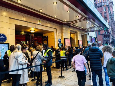 Manchester, İngiltere - 29 Eylül 2025: İnsanlar kalabalık bir Manchester tiyatrosunun önünde sıra olup, şehir yaşamını ve eğlence ortamını yakalıyorlar.