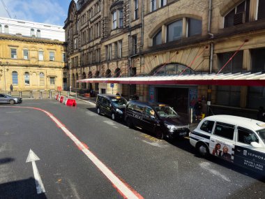 Manchester, İngiltere - 29 Eylül 2025: Kırmızı bir tepe örtüsü altında bir mağaza alanının dışındaki kamyonlar, taksiler ve yayalarla dolu Manchester caddesi.