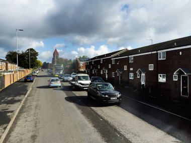 Manchester, İngiltere - 29 Eylül 2025 Manchester 'da sakin bir Waterloo caddesi tuğladan evler ve bulutlu bir gökyüzü altında park edilmiş birkaç araba.