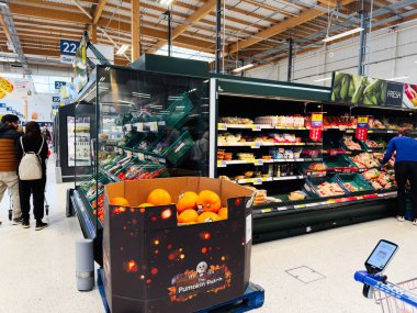 Manchester, İngiltere - 29 Eylül 2025: Müşteriler sonbaharda Manchester Tesco 'nun parlak bir süpermarketinde taze ürünlere ve mevsimlik balkabaklarına göz atıyorlar.