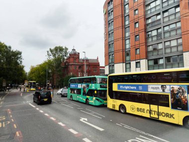Manchester, İngiltere - 29 Eylül 2025: Manchester 'da otobüsler, yayalar ve modern bir cadde boyunca mimari ile yoğun şehir manzarası.