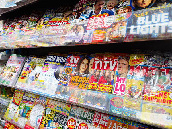 Manchester, UK - September 29, 2025: Vibrant row of magazines and tabloids on a shelf at a Manchester newsstand.