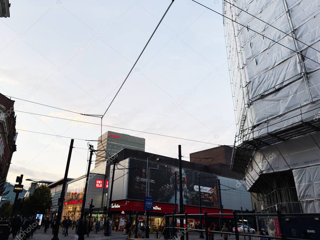 Manchester, UK - September 29, 2025: Lively urban street in Manchester with construction, shops, signs and people bustling about.