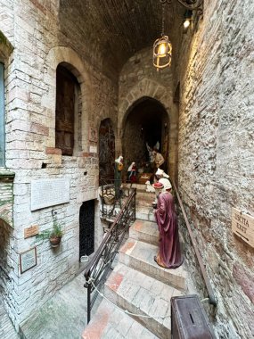 Assisi, İtalya - 16 Ekim 2024: Assisi 'de dar bir taş sokak fener ışığı altındaki basamaklar boyunca uzanan bir doğum sahnesi sunuyor.