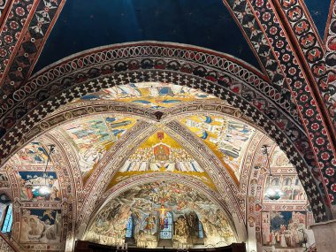 Assisi, İtalya - 16 Ekim 2024: Assisi 'de canlı freskler, kemerler ve dini sahnelerle dolu tarihi kilise tavanı.