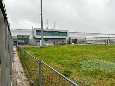 Varşova, Polonya - 25 Ekim 2024: Modern havaalanı terminali ve taksi girişi ve açık çimenli çevresi olan varış alanı.